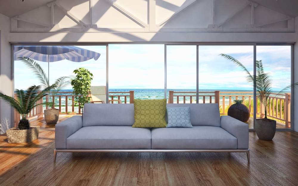 Light gray couch in living room with hardwood floors and sliding glass doors that lead to the ocean