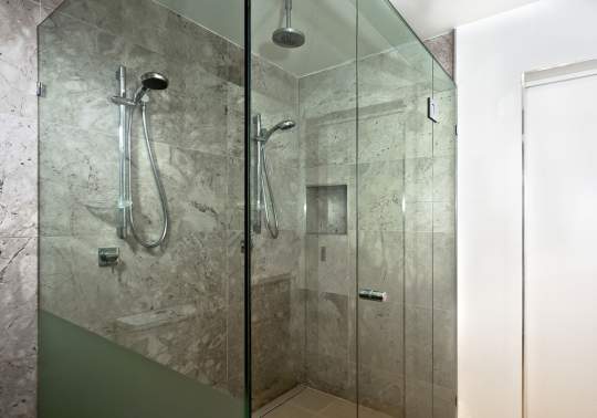 Glass enclosed shower with marble walls